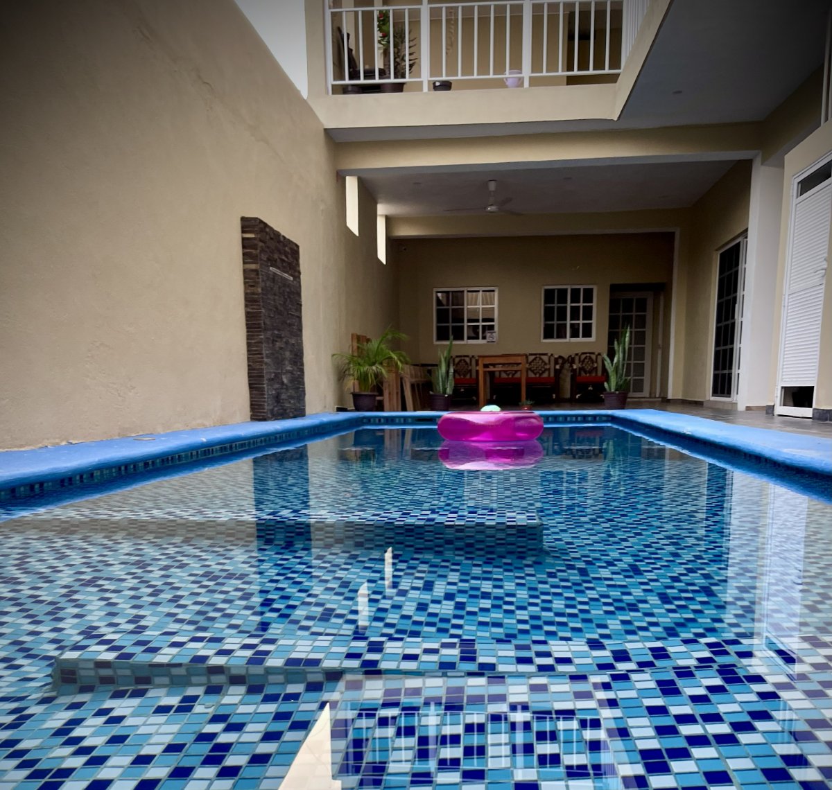 Vista de la alberca con un salvavidas rosa en hotel y bugnalows bugambilias